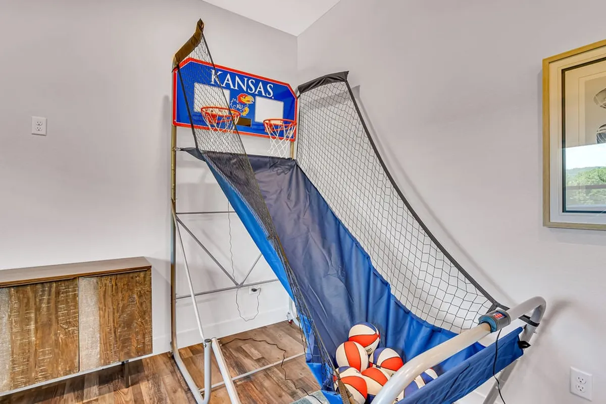 An energetic family recreation space, centered around a pop-a-shot style basketball game, with a decorative cabinet and framed artwork adding stylish touches. The space is bright and engaging, perfect for friendly competitions and gatherings.