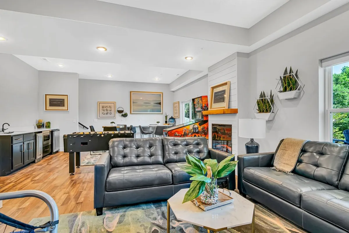 A welcoming entertainment space with black leather sofas, a foosball table, and a warm fireplace. The area is designed for casual socializing, playing games, and relaxing, blending comfort with spirited play.