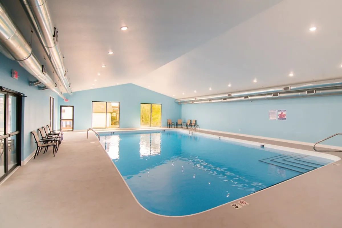 A serene indoor swimming pool, bathed in natural light from large windows, with comfortable seating nearby. The inviting atmosphere suits year-round relaxation and social gatherings, regardless of the weather outside.